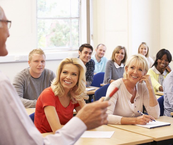 Teilnehmer des Sprachkurses schauen lächelnd zum Lehrer